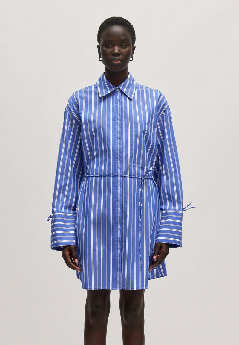 Gestreiftes Hemdkleid in Hellblau und Weiß, ausgestattet mit einem Kragen, langen Ärmeln mit Bindebändern und einer taillierten Taille für eine enganliegende Silhouette.