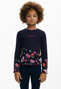Marineblaue Langarmoberteil mit bunten Blumen- und Schmetterlingsmustern, geripptem Stoff und gewelltem Saum. Mit dem Schriftzug "desigual" in roter Schrift.