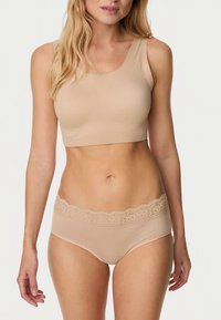 Tělová bezšvová podprsenka se širokým pásem a krajkovým lemem v kombinaci s odpovídajícím kalhotkami. Oba kusy mají jemnou, hladkou texturu a přiléhavý střih.