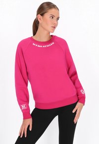 Sudadera rosa con cuello redondo, puños y dobladillo acanalados, con la inscripción "MYMO ATHLRS" en letras blancas y un detalle gráfico en la manga.
