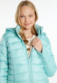 Jachetă puf light turquoise cu glugă, închidere cu fermoar și design matlasat. Interiorul are un material moale de culoare crem.