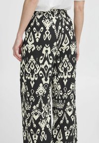 Pantalon large à motif noir et blanc avec un tissu texturé, présentant un design abstrait unique et une taille élastique.
