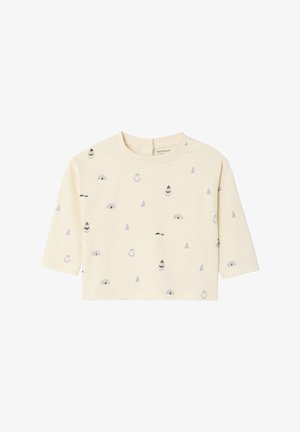 Light yellow cropped long-sleeve shirt featuring small gray penguin and igloo patterns, with a round neckline and back button closure.