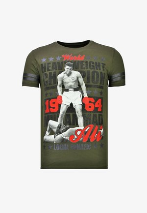 Groen T-shirt met zwarte en rode tekst waarop bokser Muhammad Ali staat afgebeeld terwijl hij boven een gevallen tegenstander staat, met de tekst "Wereldkampioen zwaargewicht 1964".