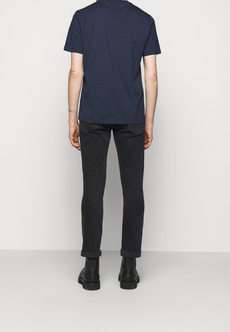 Navy blue cotton t-shirt with short sleeves paired with slim-fit black jeans. The jeans feature rolled cuffs and black ankle boots.