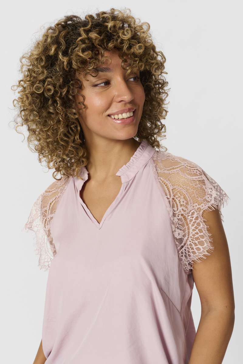 Blusa rosa con scollatura a V, maniche corte in pizzo e tessuto morbido e leggero. Il bordo in pizzo aggiunge un delicato dettaglio di design.
