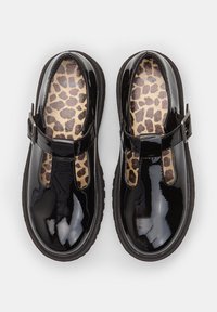 Zwarte lakleren schoenen hebben een T-bar ontwerp met een zilveren gesp. Aan de binnenkant contrasteert een panterprintzool met de buitenafwerking.