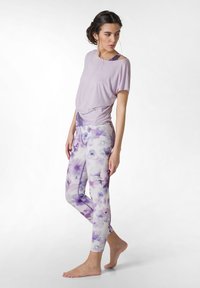 Ljuslila kortärmad topp med avslappnad passform, tillsammans med åtsittande leggings med mjukt blommönster i nyanser av lila och vitt.