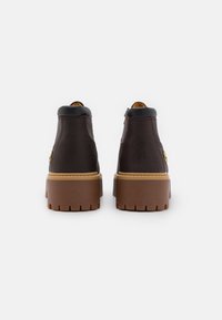 Stivaletti in pelle marrone con finitura testurizzata, colletto imbottito nero e suola in gomma marrone con motivo a zigzag.