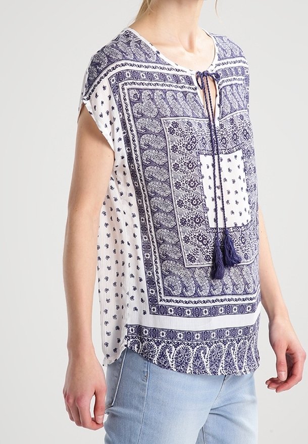 Námořnická a bílá košile s krátkými rukávy, výstřihem do V a třásňovým vázáním. Obsahuje geometrické a květinové vzory po celém povrchu.