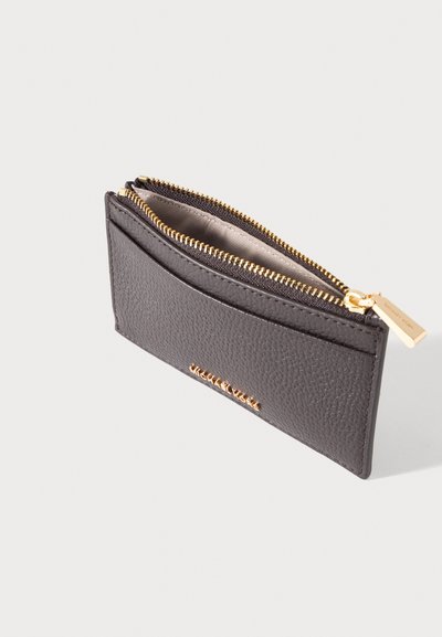 Petit porte-cartes en cuir marron foncé avec fermeture éclair dorée et poche extérieure pour cartes, placé sur un fond clair.