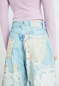 Lichtblauwe patchwork jeans met gemengde stoffen zakken in bloemen-, geruite en kantpatronen. Schone denimafwerking met een label op de tailleband.