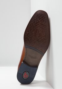 Semelle de chaussure en cuir marron avec un motif texturé, logo en relief et une section en caoutchouc bleu contrastant. Design épuré et moderne.