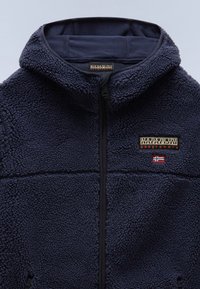 Chaqueta de forro polar azul marino con capucha, cremallera frontal, parche con el logo de Napapijri y pequeño emblema de bandera en el pecho.