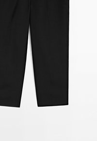 Pantaloni neri a gamba dritta con orlo pulito su sfondo bianco, che mostrano la metà inferiore delle gambe.