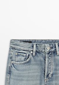 Jean en denim bleu clair délavé avec bouton frontal, fermeture éclair, passants de ceinture et détail de petite poche avant effilochée.