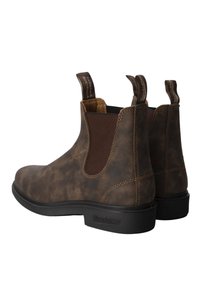 Brązowe skórzane botki za kostkę z elastycznymi panelami bocznymi i uchwytami. Teksturalna powierzchnia z kontrastującymi szwami i czarną gumową podeszwą.