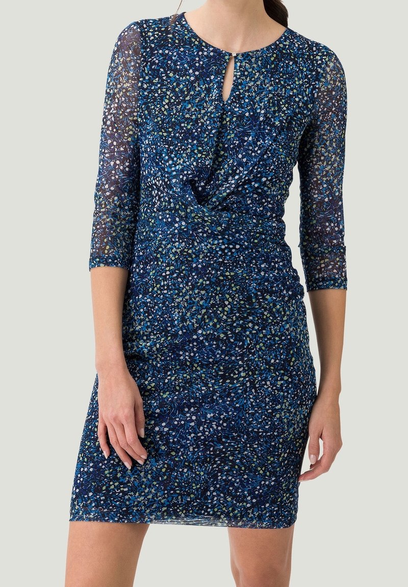 Kurzärmliges Kleid in Marineblau mit einem strukturierten Blumenmuster in Grün und Weiß. Mit einem Schlüssellochausschnitt und taillierter Silhouette.