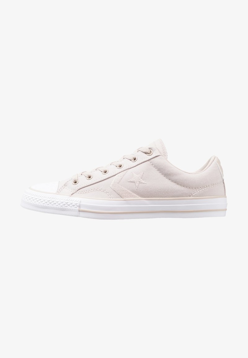 Baskets basses beige clair avec semelle en caoutchouc blanche, logo en forme d’étoile sur le côté et fermeture à lacets.