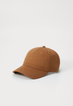 Brun Calvin Klein baseballkasket med buet skygge og broderet logo på frontpanelet, vist på hvid baggrund.