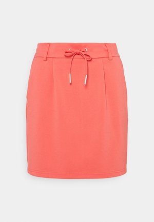 Coral pink knee-length skirt with front tie string, belt loops, and subtle front pleats on plain background.