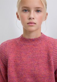 Suéter tejido en tonos rosa y púrpura, con un cuello acanalado y detalle en el hombro, que muestra una textura suave.