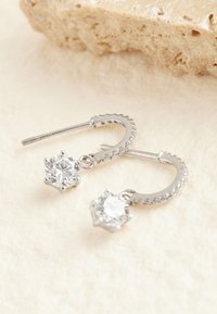 Pendientes de aro de plata con borde texturizado, con dos piedras de imitación claras colgantes en engastes en forma de estrella. Metal liso y detalles brillantes.