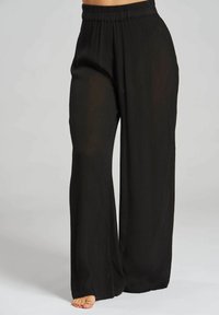 Pantaloni neri a gamba larga con texture plissettata e vita elastica, realizzati in tessuto leggero. Dettagli includono una silhouette fluida.