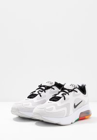 Sneakers med en överdel i huvudsak av vit mesh, svart snörning, grå detaljer och en färgglad luftkudding i sulan.