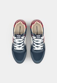 Mørkeblå og rød sneaker med hvide snørebånd, mesh- og ruskindmaterialer, afrundet tå og polstret krave. Mærkets logo på tungen.