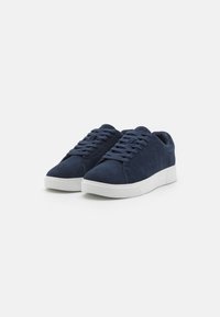 Mörkblåmocka sneakers med vita gummisulor, rund tå och plana snören. Har en slät yta och en minimalistisk design.