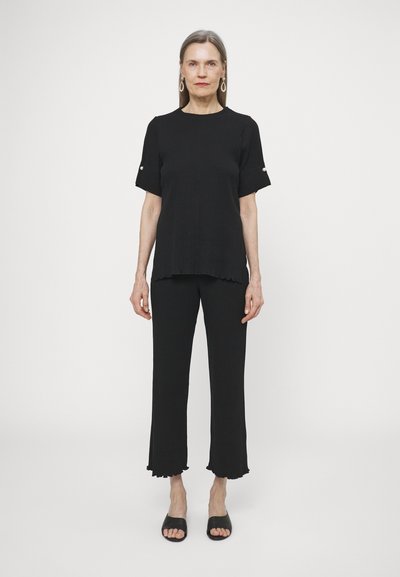 Black two-piece outfit featuring a short-sleeve top with a rounded hem and textured ribbed pants with flared cuffs and subtle details.