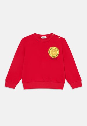 Pull enfant rouge à manches longues avec poignets côtelés, un emblème solaire jaune, logo Versace sur la poitrine et deux boutons dorés près du col.