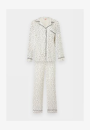 Ensemble de pyjama blanc à manches longues avec motif triangulaire noir, passepoil noir sur le col, les poignets, la poche et le bas du pantalon, fermeture boutonnée devant.