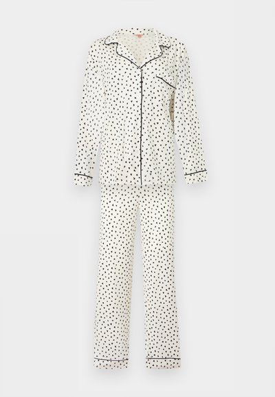 Λευκή πυτζάμα με μακριά μανίκια και μαύρο μοτίβο σε σχήμα τριγώνου, μαύρες λεπτομέρειες στον γιακά, στα μανίκια, στην τσέπη και στα τελείωμα των παντελονιών, με κουμπιά μπροστά.