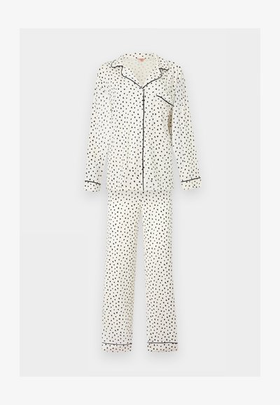 Λευκή πυτζάμα με μακριά μανίκια και μαύρο μοτίβο σε σχήμα τριγώνου, μαύρες λεπτομέρειες στον γιακά, στα μανίκια, στην τσέπη και στα τελείωμα των παντελονιών, με κουμπιά μπροστά.
