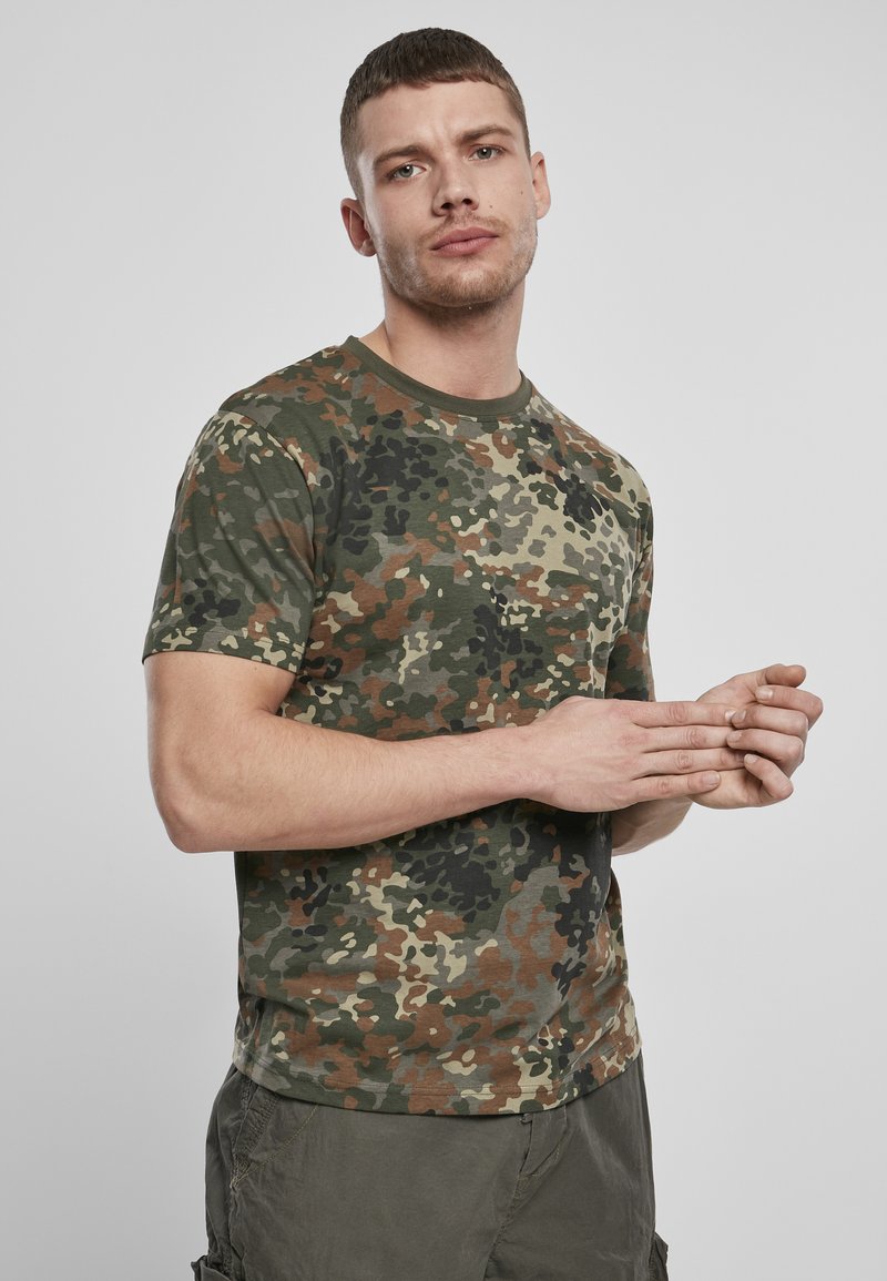 Žalias kamufliažo rašto T-shirt iš minkštos medžiagos, su trumpomis rankovėmis ir apvaliu kaklu, derinamas su alyvuogių spalvos šortais.