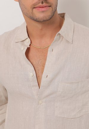 Chemise en lin beige clair avec une coupe décontractée, un col boutonné, une poche avant et un tissu texturé. Comprend des boutons et un décolleté profond.