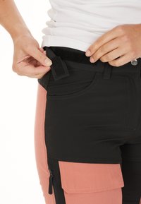 Zwarte en roze broek met een rits-kargo zak, voorzien van een klittenbandsluiting bij de taille en een gladde, rekbare stof.