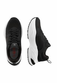 Schwarze Sportschuhe mit dicken weißen Sohlen, Schnürsenkeln und Schlaufe zum Hochziehen, aus der Vogelperspektive und von der Seite auf einem weißen Hintergrund gezeigt.