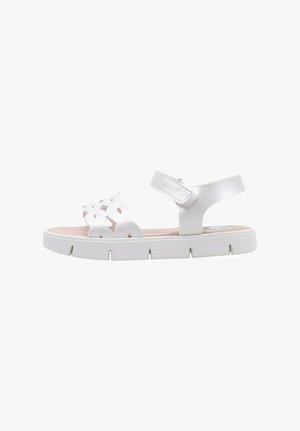Sandal blanc avec un design découpé sur les brides et une sangle de cheville ajustable, dotée d'une épaisse semelle blanche et d'une semelle intérieure rose.