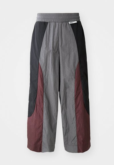Pantalons à large jambe en tissu léger, présentant un design en blocs de couleur noir, gris et bordeaux avec une taille élastique.