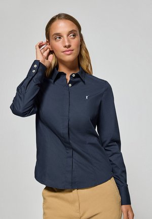 Navy blue button-up shirt with a tailored fit, long sleeves, and a small logo on the left chest. Smooth texture and classic collar design.