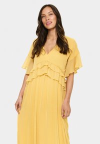 Yellow, pleated dress with a V-neck and layered ruffles on the bodice. Lightweight, flowing fabric with short, flared sleeves.