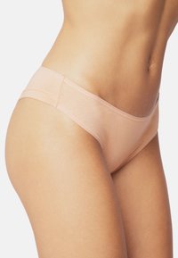 Mutandine hipster in cotone pesca con una texture liscia, design a vita bassa e elastico in vita, esposte sul torso inferiore.