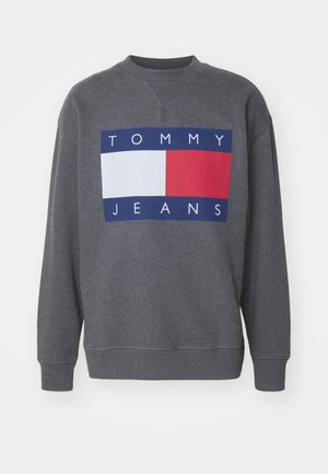 Sweatshirt gris foncé à col rond avec poignets et ourlet côtelés, arborant un grand logo Tommy Jeans avec des blocs de couleur blanc et rouge sur la poitrine.