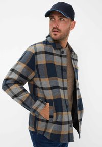 Knoop-up flanellen shirt in blauw, grijs en bruin geruit. Voorzien van een kraag, lange mouwen en zijzakken. Zachte textuur, casual ontwerp.