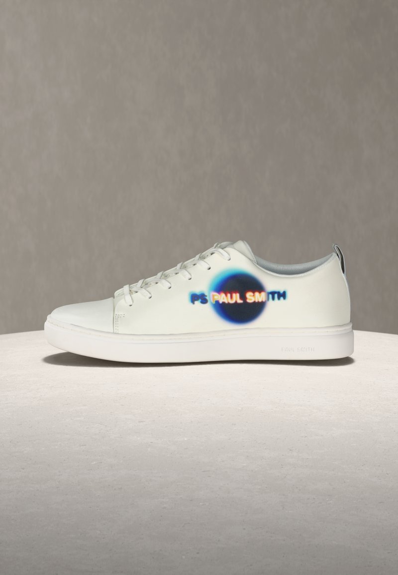 Baskets blanches basses avec lacets, arborant un logo flou multicolore "PS PAUL SMITH" sur un cercle noir sur le côté.