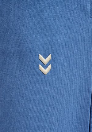 Białe podwójne logo w kształcie jodełki wyhaftowane na niebieskiej prążkowanej tkaninie, wyśrodkowane pionowo w zbliżeniu.