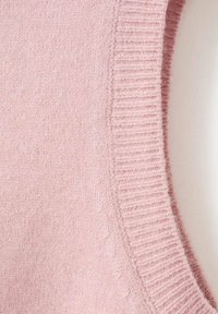 Svjetloružičasti pleteni džemper s rebrastim okruglim izrezom i mekanom teksturom, s glatkim tijelom i suptilnim sitnim mrljama unutar materijala.